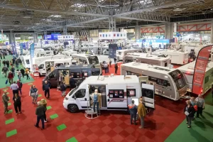 A crowd inside the pavilion of a caravan show are looking through all the vehicles and products on display