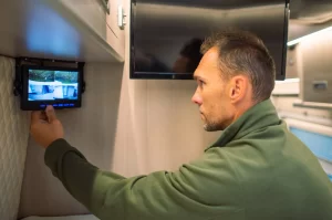 A man is checking the CCTV security cameras on a screen inside his caravan