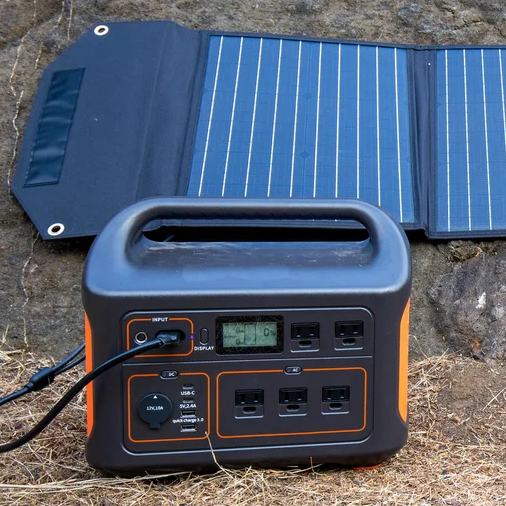 A portable battery setup being charged by a solar blanket.