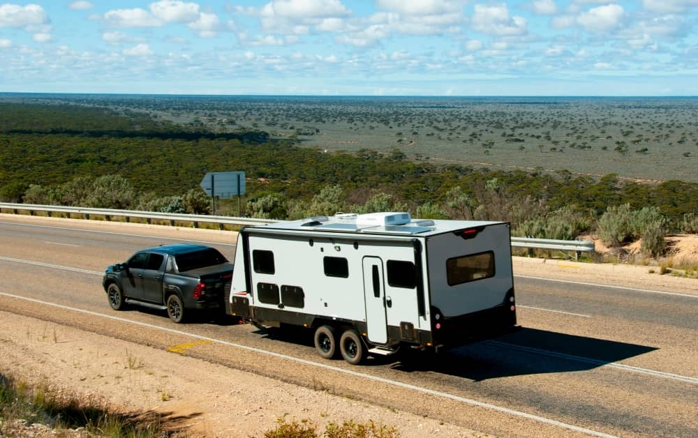 A caravan being towed behind a Toyota Hilux on a highway in outback Australia.